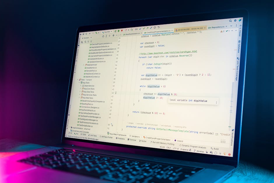 A close-up view of a laptop screen displaying lines of programming code, with a dark background illuminated by a soft blue and pink glow, suggesting a dimly lit environment. The code includes syntax h
