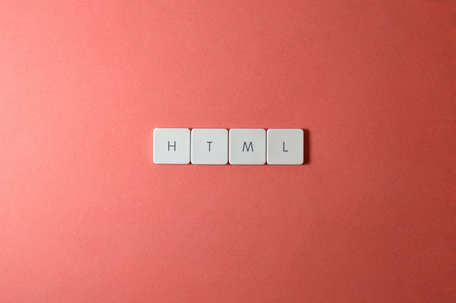 A close-up image of four white square tiles arranged in a horizontal line on a coral pink background. Each tile features a black letter, spelling out 'HTML'. The tiles have a smooth, matte finish with